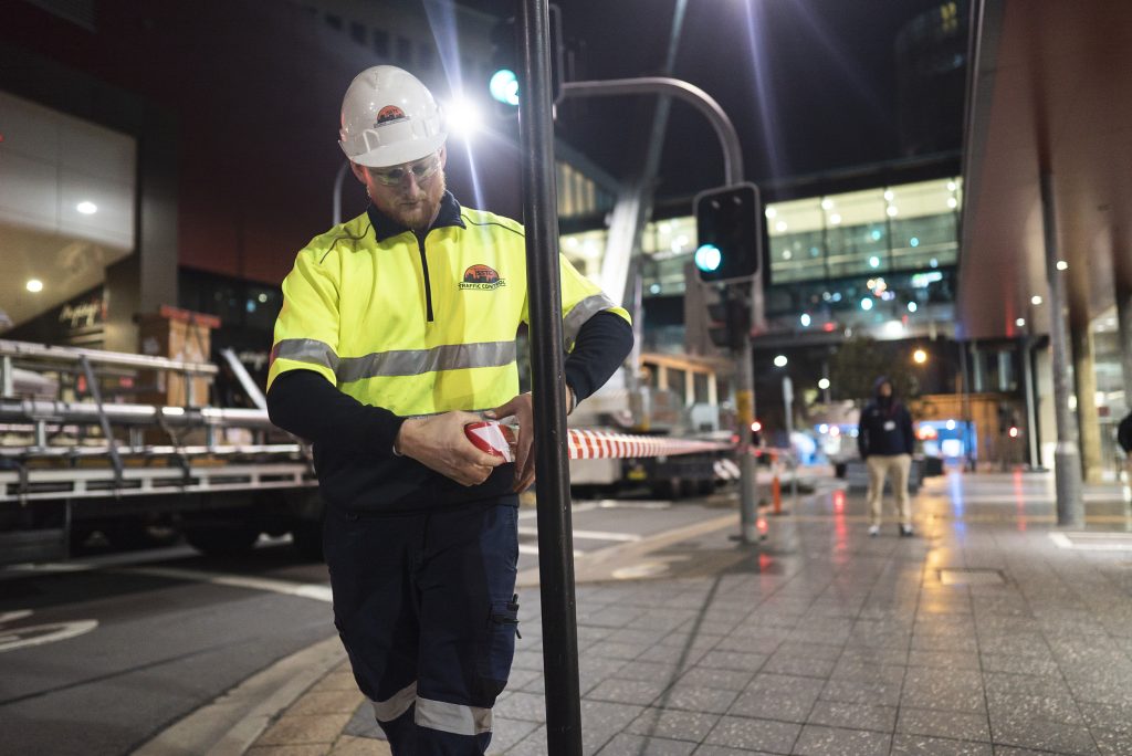 A traffic control wearing reflective wear rolling out tape to section of an area. 