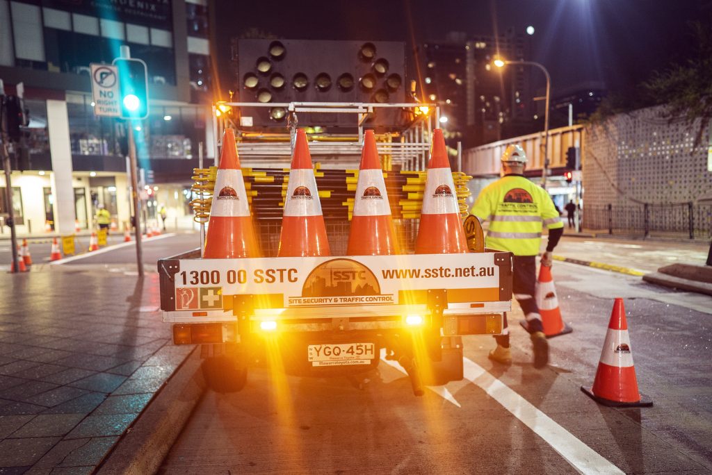 An SSTC traffic control Ute with its hazards on. A traffic controller is packing up next to it. 